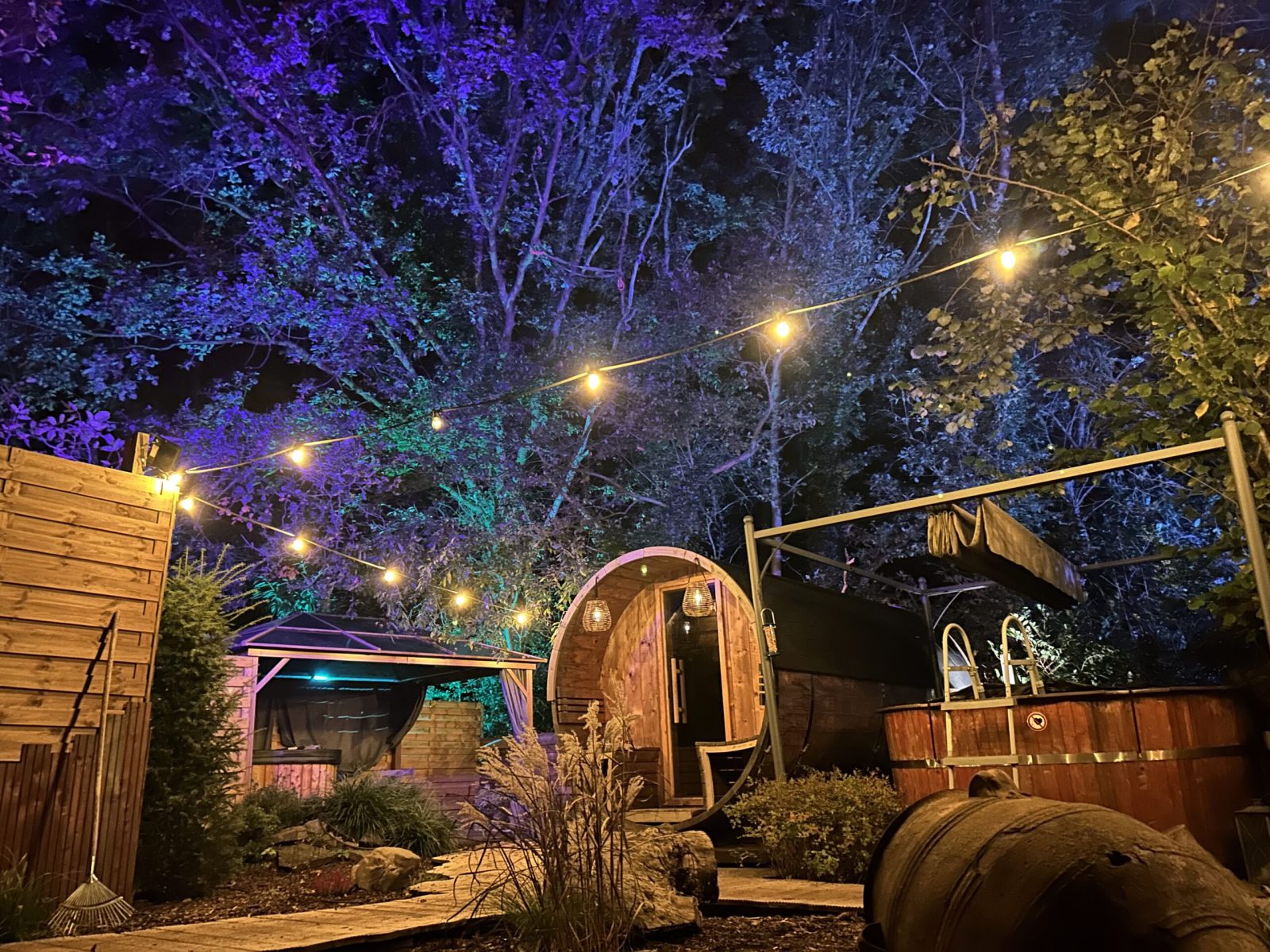 De tuin 's avonds, met lichtjes boven de tonsauna en de hottub